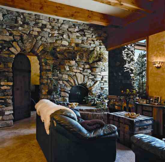 A see-through fireplace, topped by a found-log mantle, warms the 6,000-pound hearth stone found on the property. The stone retains warmth and releases it slowly into both the main room and the bedroom. The rough-sawn kiln-dried beams are locally milled and left in their natural state to eliminate toxic stains and sealants.